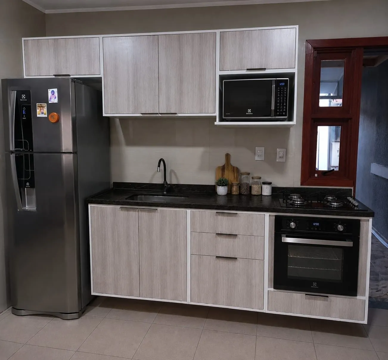 Cozinha planejada amadeirada clara com forno e micro-ondas embutidos