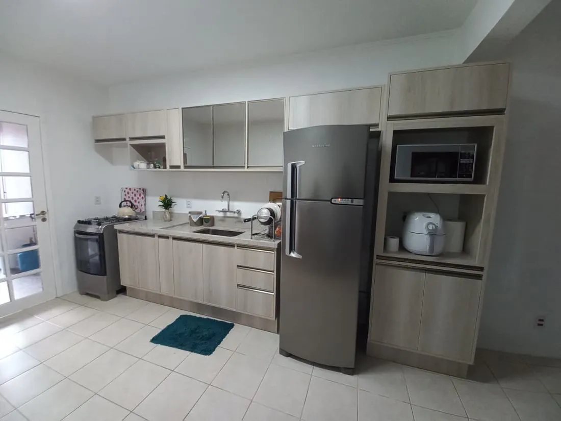 Cozinha clara com torre de micro-ondas e armários com espelho