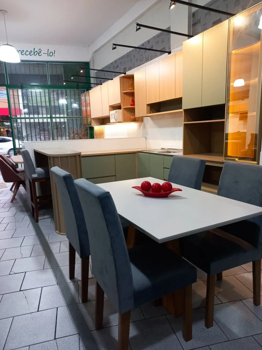 Cozinha verde e mesa de jantar montadas no showroom